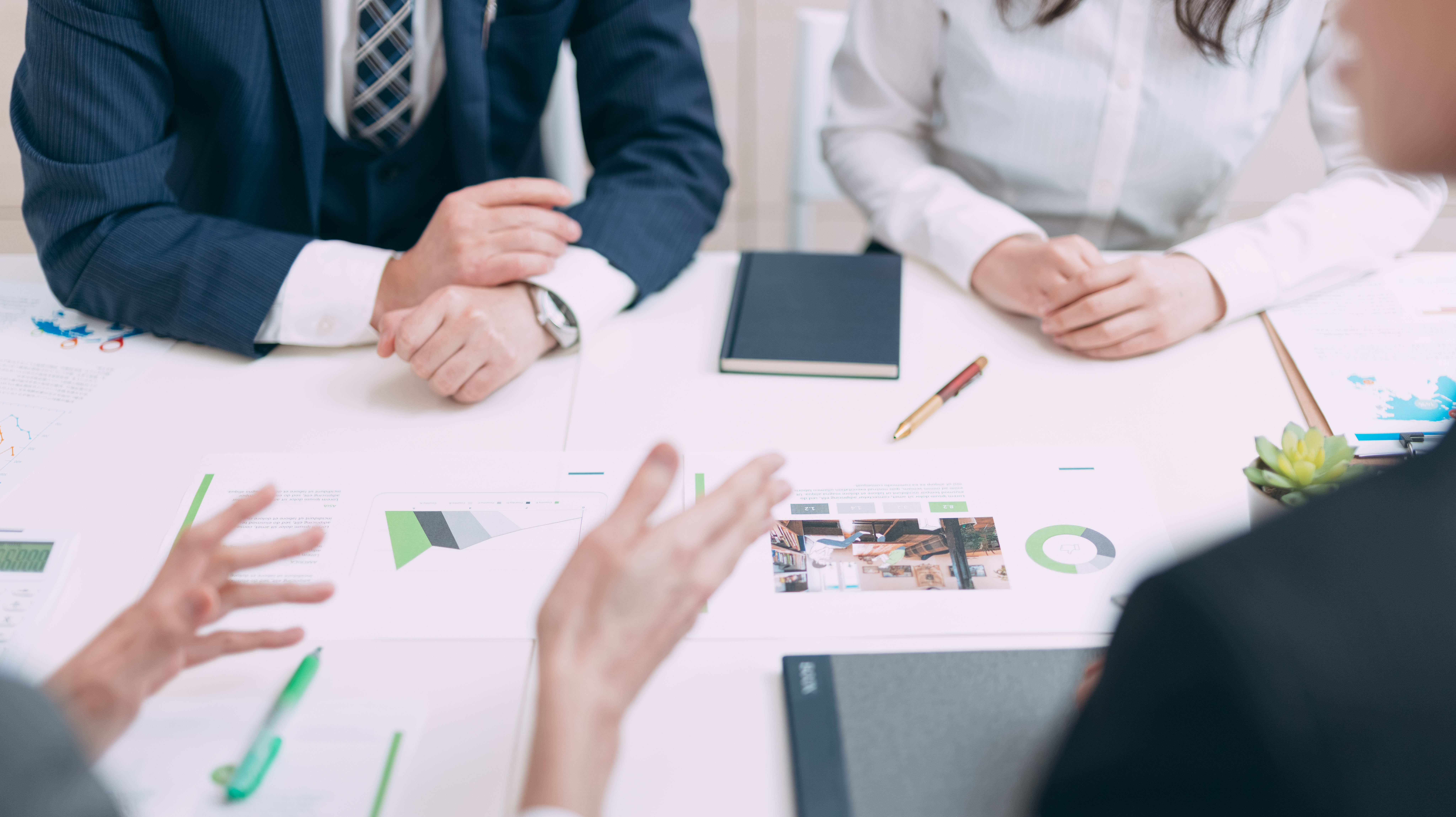 ノートPCを使い、資料を見ながら意見交換をするビジネスパーソンたち